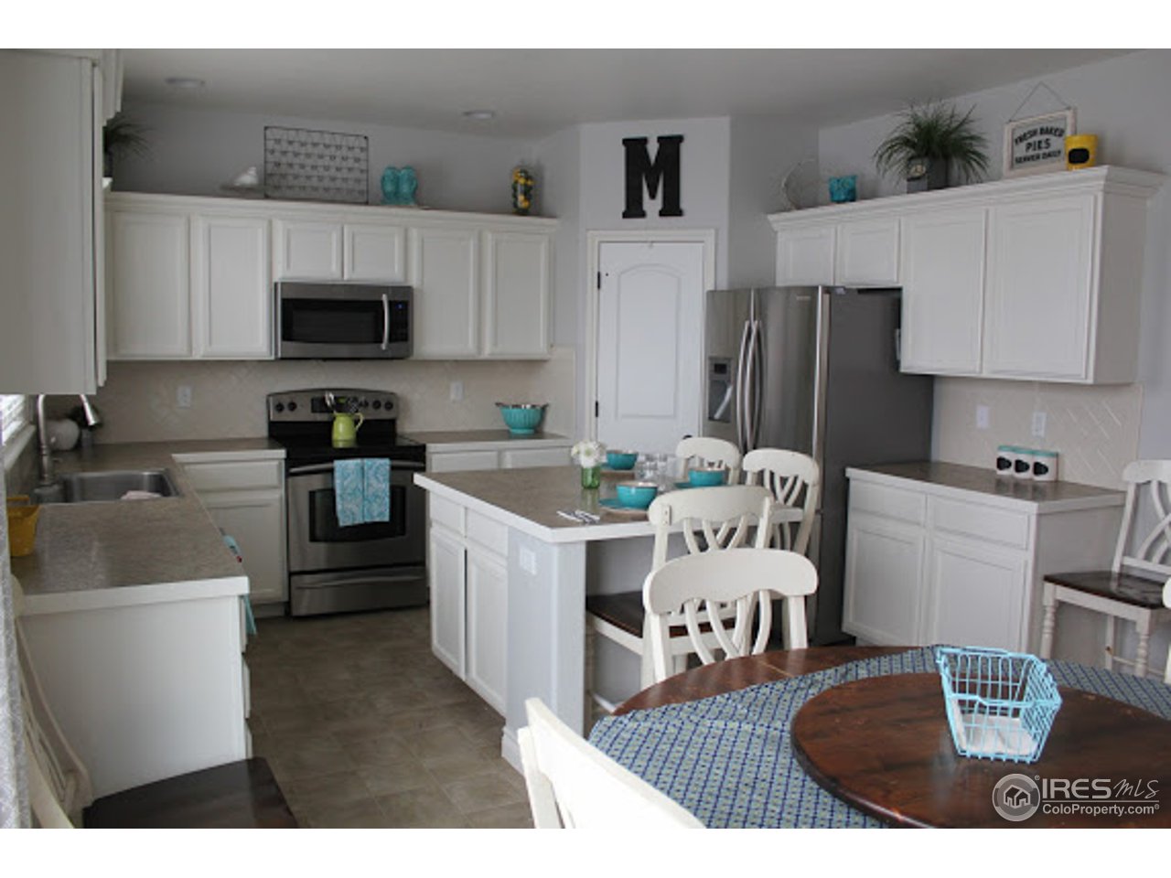 2259 80th Avenue Greeley, CO 80634 - Photo 2 of 21 a kitchen with a sink dishwasher a stove a microwave a refrigerator and cabinets with wooden floor