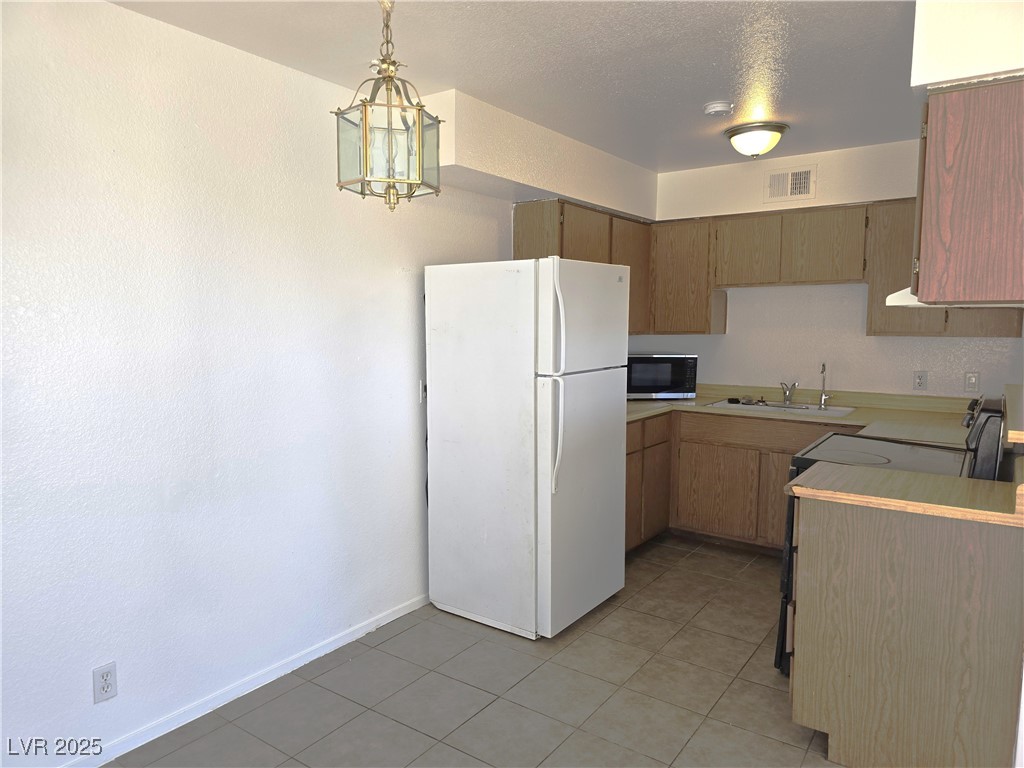 1812 Fulstone Way, Unit 3 Las Vegas, NV 89115 - Photo 2 of 12 Kitchen with light countertops, freestanding refrigerator, electric range, pendant lighting, and light tile patterned flooring