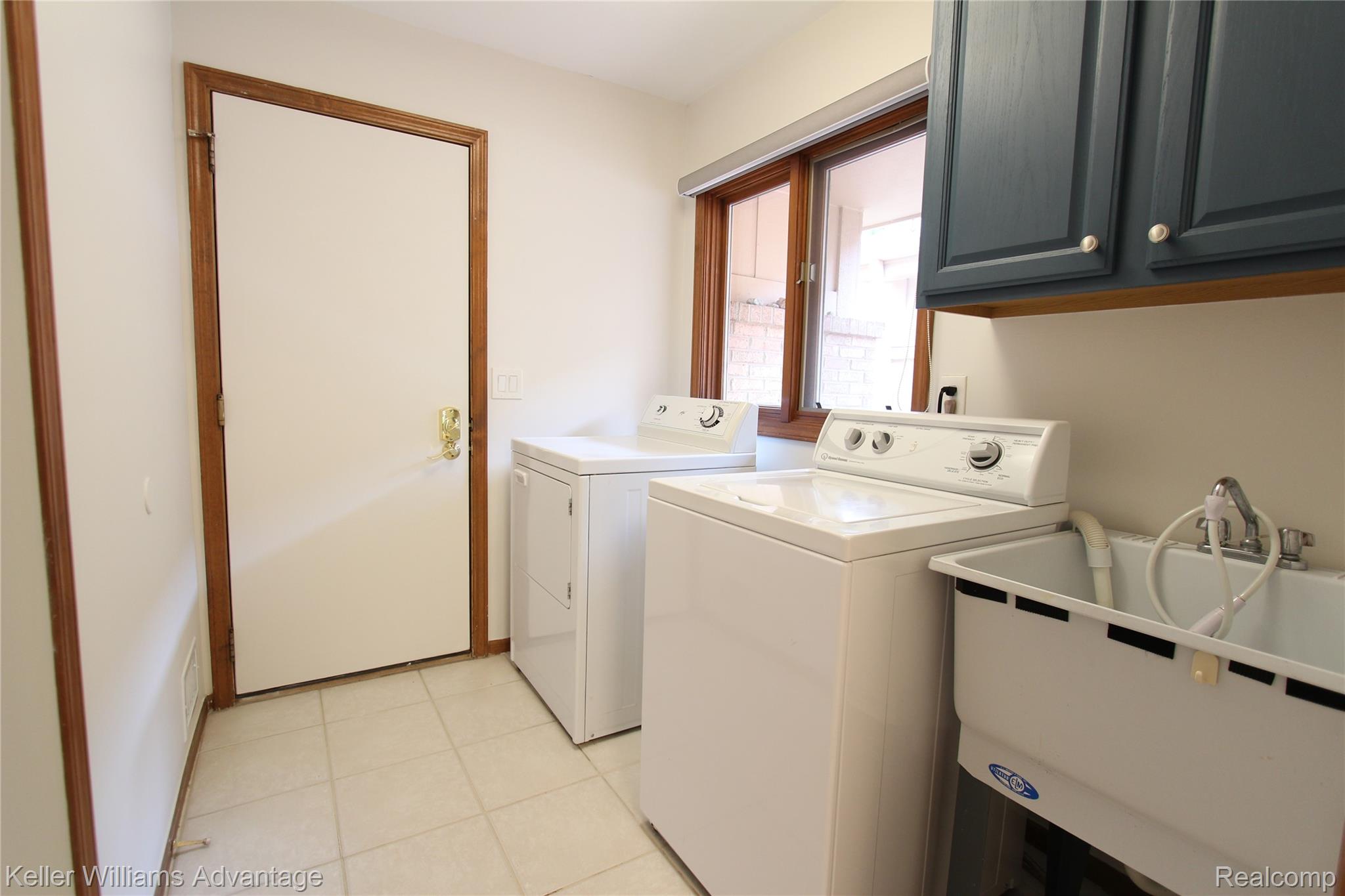 21850 River Ridge Trail Farmington, MI 48335 - Photo 5 of 33 Dedicated laundry area featuring a utility sink with sprayer, overhead blue cabinetry, and tiled flooring