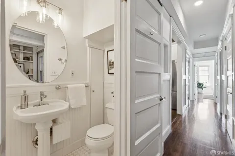 a view of a hallway with wooden floor and a bathroom