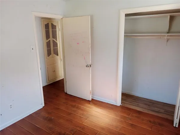 a view of an empty room with wooden floor and closet