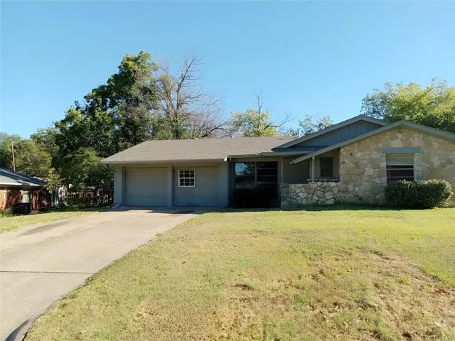 a front view of house with yard and trees in the background