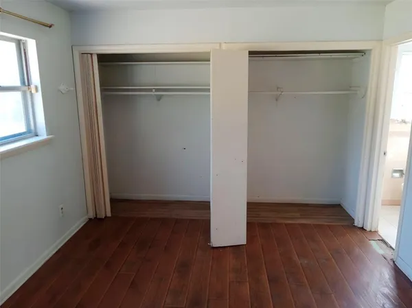 an empty room with wooden floor and closet