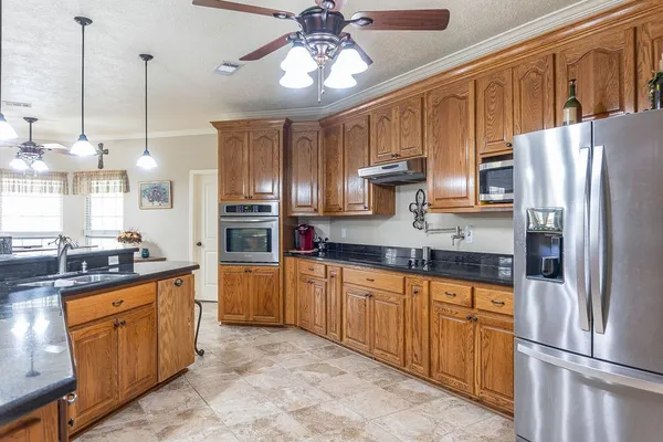 a kitchen with stainless steel appliances granite countertop a refrigerator a oven a sink with granite countertop cabinets and refrigerator