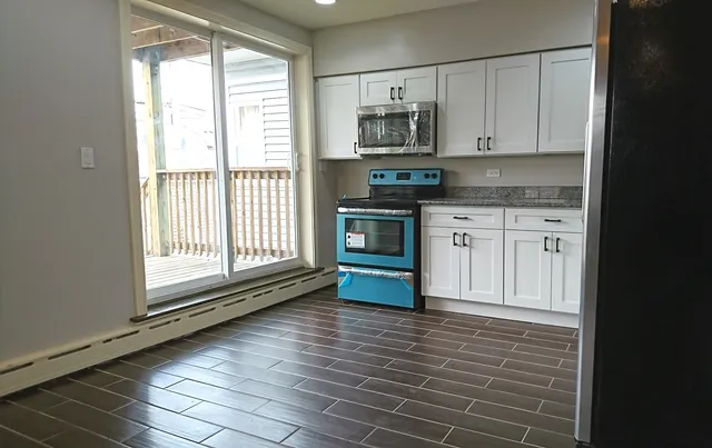 a kitchen with stainless steel appliances granite countertop a stove a sink and white cabinets