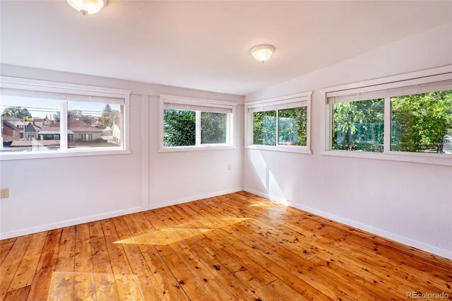 a view of an empty room with a window and wooden floor