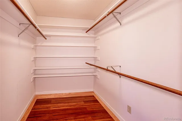 a view of a hallway with wooden floor and a bathroom