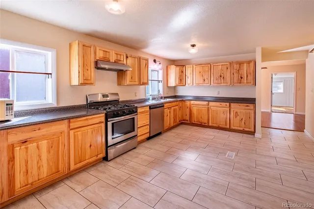 a large kitchen with stainless steel appliances granite countertop a stove sink and cabinets
