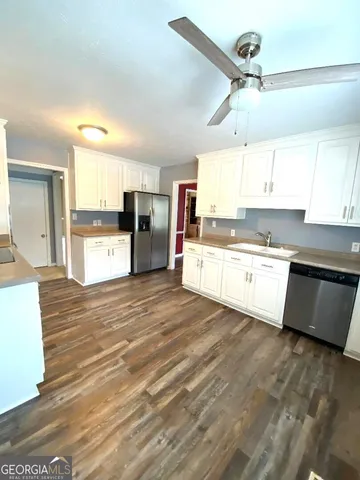a kitchen with granite countertop a stove a sink and white cabinets with wooden floor