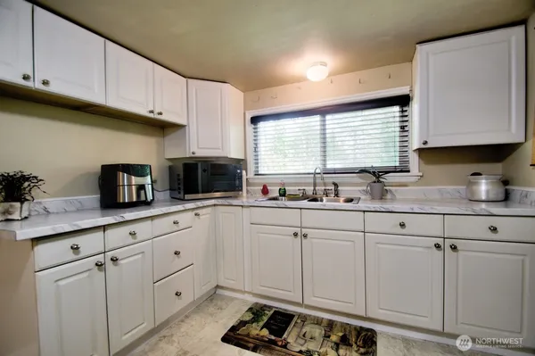 a kitchen with white cabinets and sink