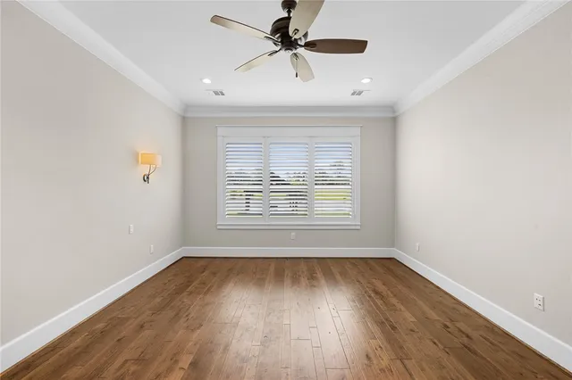 an empty room with wooden floor ceiling fan and windows