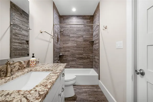 a bathroom with a granite countertop sink toilet and shower