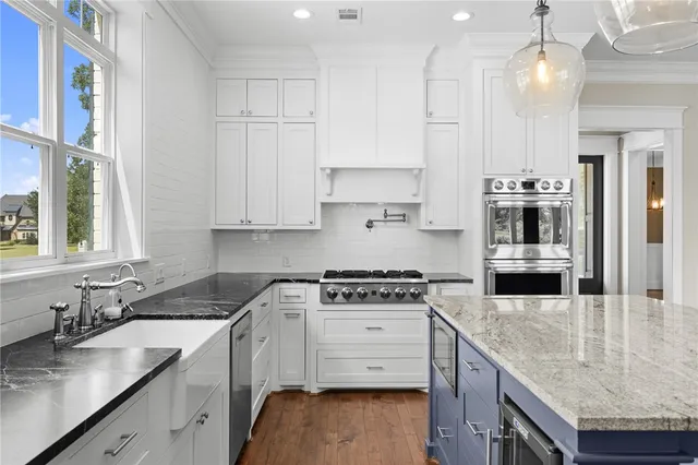 a kitchen with granite countertop a stove a sink and a refrigerator