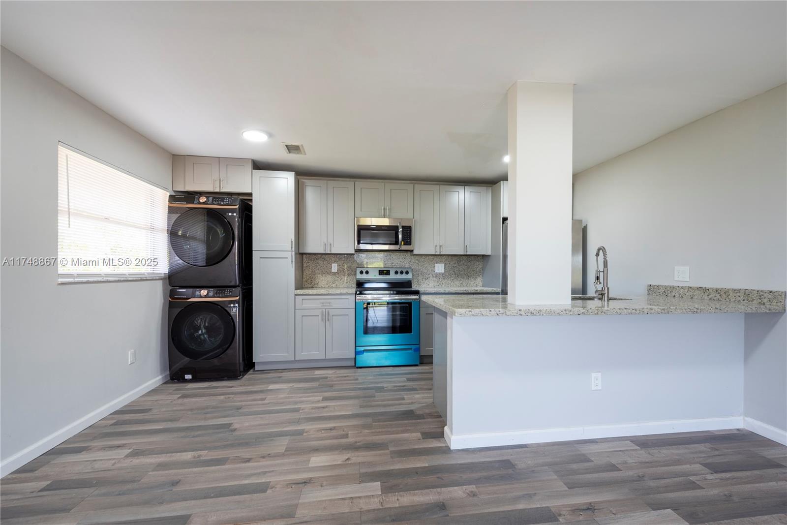 a kitchen with granite countertop a refrigerator stove and wooden floor