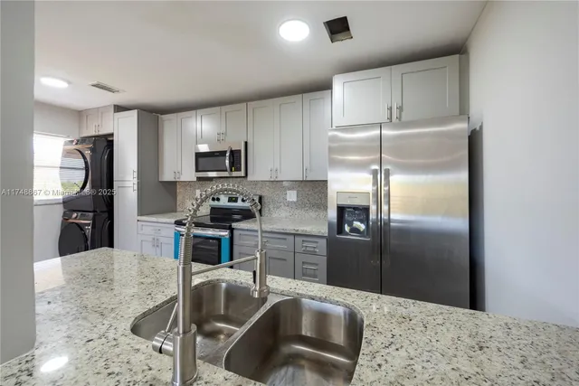 a kitchen with granite countertop a refrigerator and a sink