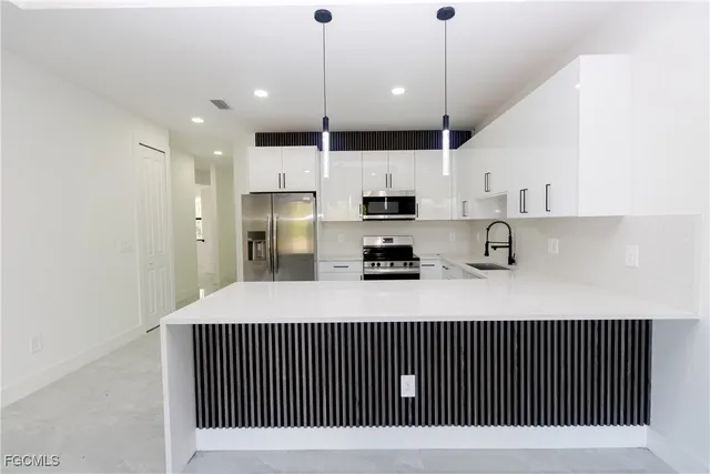 a kitchen with stainless steel appliances granite countertop a stove a sink a refrigerator and white cabinets