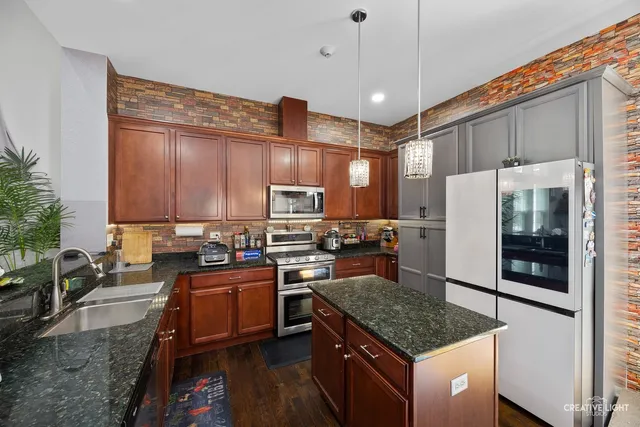 a kitchen with stainless steel appliances granite countertop a stove refrigerator sink and microwave