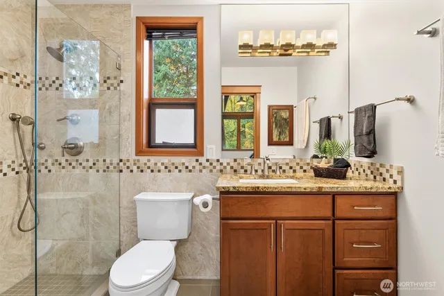 a bathroom with a granite countertop toilet sink and mirror