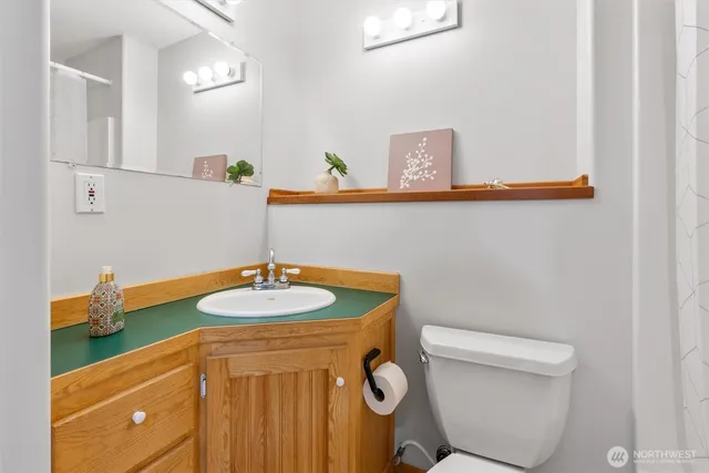 a bathroom with a granite countertop toilet sink and mirror