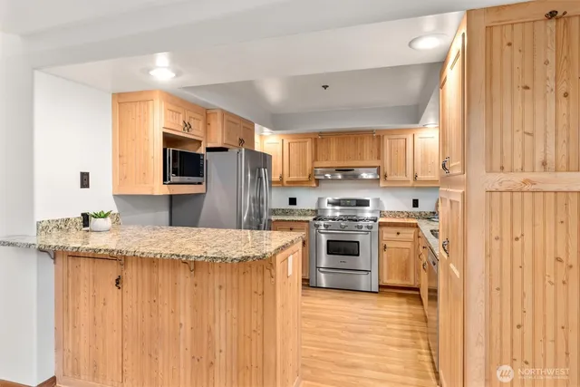 a kitchen with stainless steel appliances granite countertop a stove a sink a microwave oven and a refrigerator