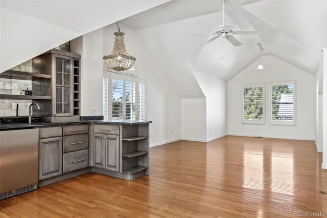 an empty room with wooden floor chandelier and windows