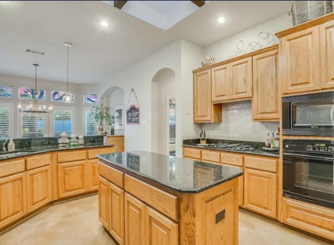 413 Breakaway Road Cedar Park, TX 78613 - Photo 10 of 21 Kitchen featuring dark stone counters, black appliances, a center island, arched walkways, and light wood finish cabinets