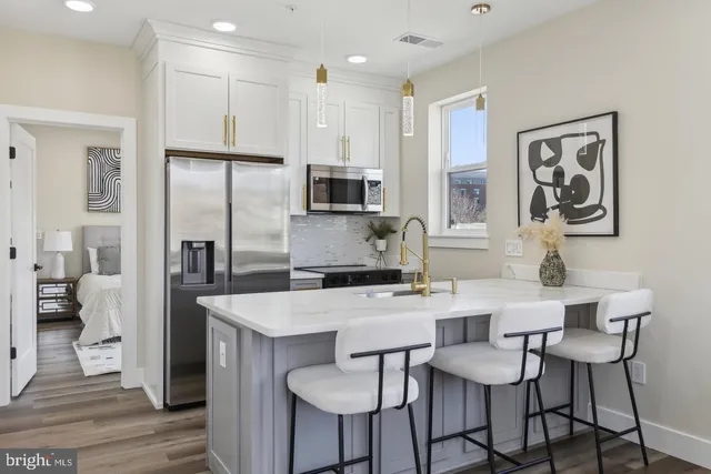 a kitchen with stainless steel appliances kitchen island granite countertop a dining table chairs refrigerator and sink