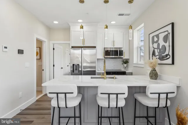a kitchen with stainless steel appliances a dining table chairs refrigerator and sink