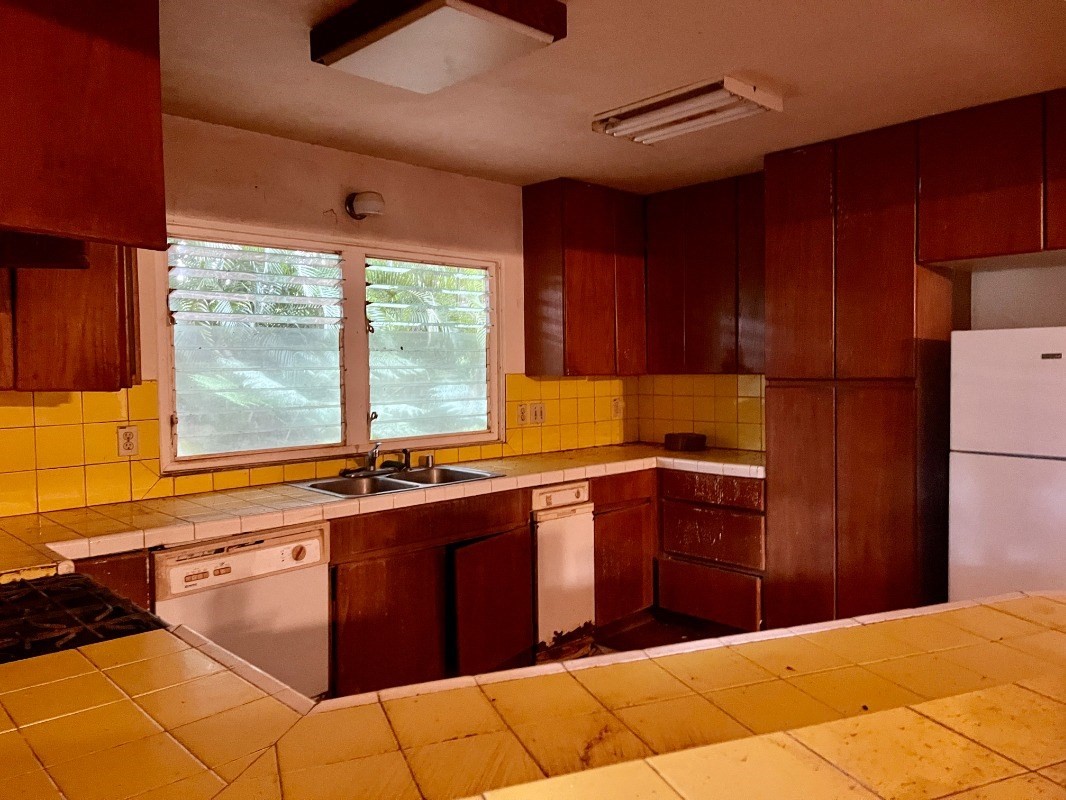 6296 Olohena Road Kapaa, HI 96746 - Photo 10 of 30 a kitchen with stainless steel appliances granite countertop a sink dishwasher stove and refrigerator with wooden floor