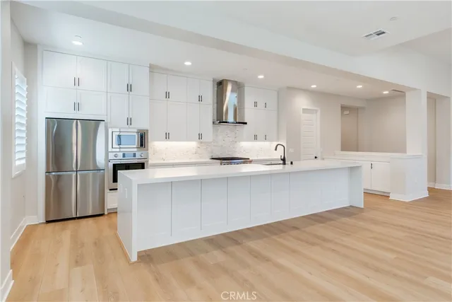 a large white kitchen with a refrigerator a stove a sink and a oven