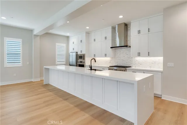 a kitchen with stainless steel appliances granite countertop a sink a stove a refrigerator and white cabinets