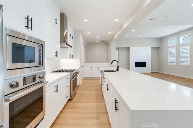 a large white kitchen with stainless steel appliances granite countertop a stove a sink and a microwave