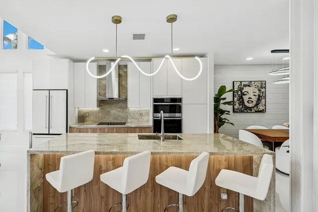 a kitchen with stainless steel appliances kitchen island granite countertop a table and chairs in it