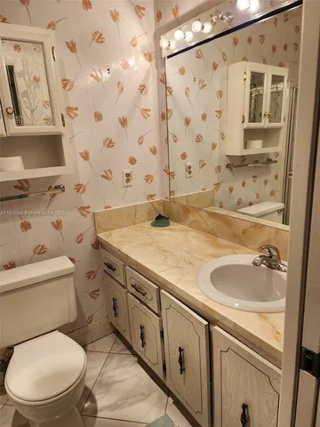 a bathroom with a granite countertop toilet sink and mirror