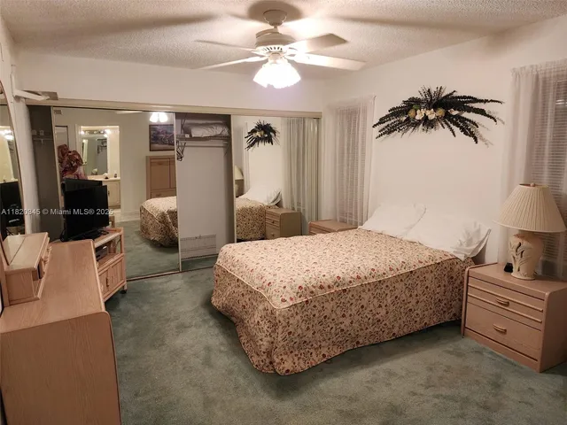 a spacious bedroom with a bed a couch and a chandelier fan