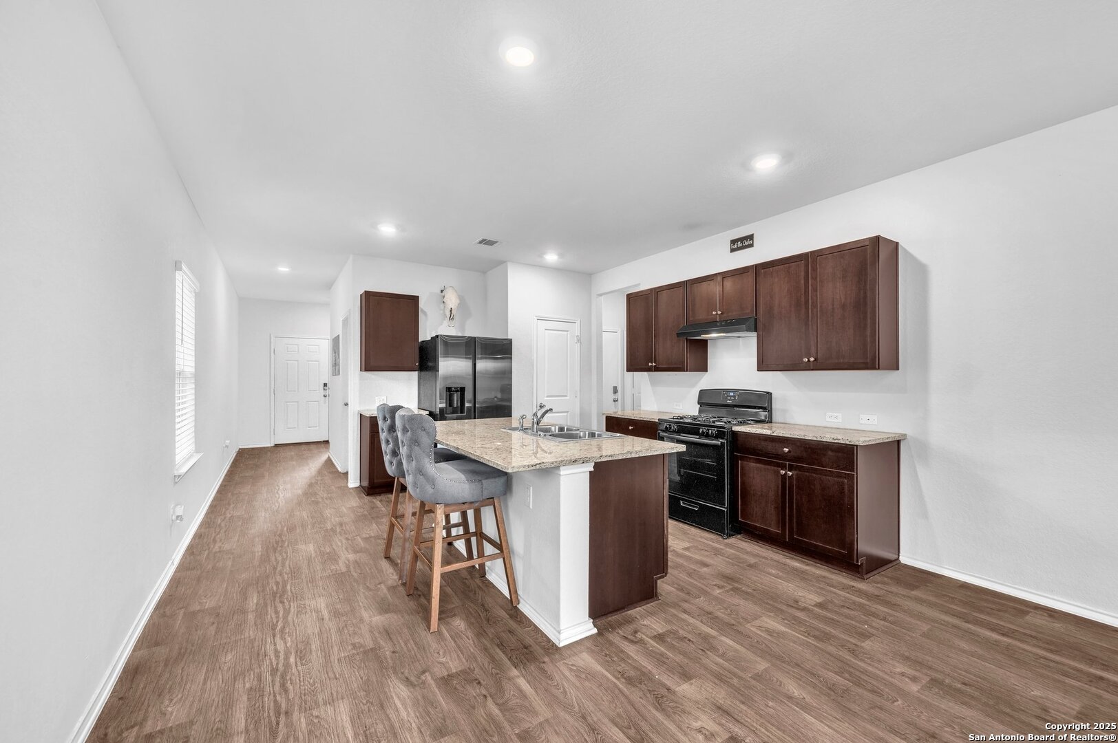 14016 Breccia Loop San Antonio, TX 78253 - Photo 5 of 31 a kitchen with stainless steel appliances granite countertop a stove top oven a sink dishwasher a refrigerator and a dining table with wooden floor