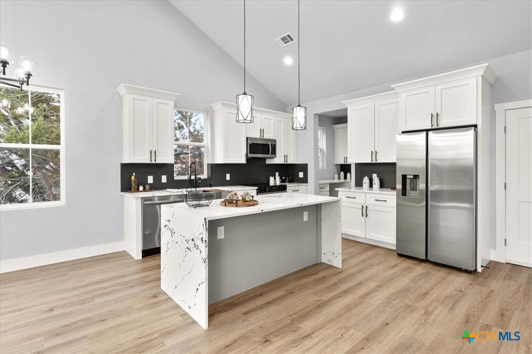 1190 Fernwood Road Fischer, TX 78623 - Photo 12 of 27 a kitchen with stainless steel appliances kitchen island a refrigerator a sink dishwasher a stove and white cabinets with wooden floor