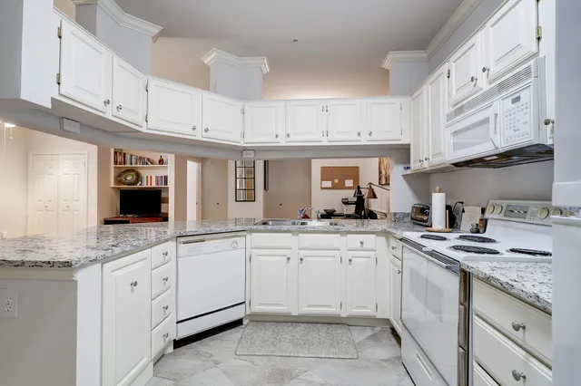 a kitchen with granite countertop white cabinets and white appliances