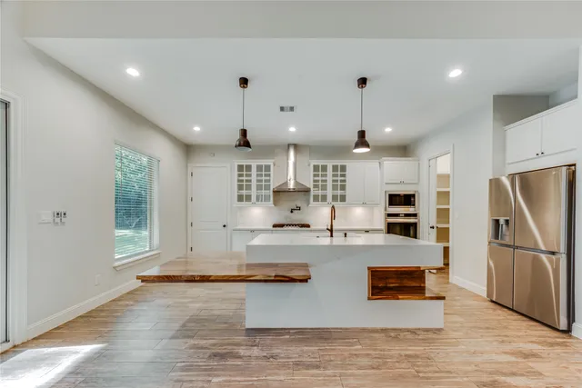 a kitchen with stainless steel appliances granite countertop a refrigerator a oven and a sink