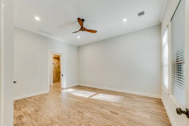 a view of empty room with wooden floor and fan