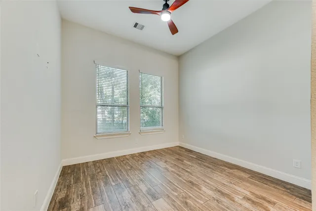 an empty room with a window and a ceiling fan