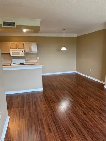 a view of kitchen and empty room with wooden floor