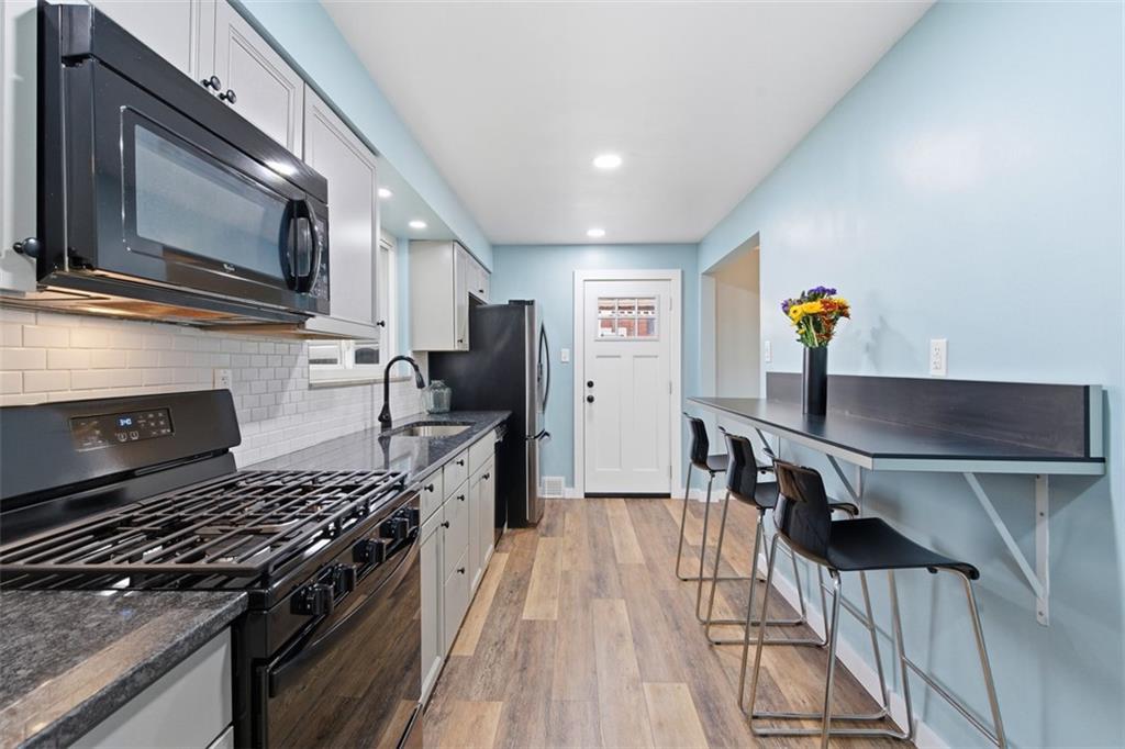 111 Crest Drive Monaca, PA 15061 - Photo 7 of 37 a kitchen with a stove a microwave and wooden floor