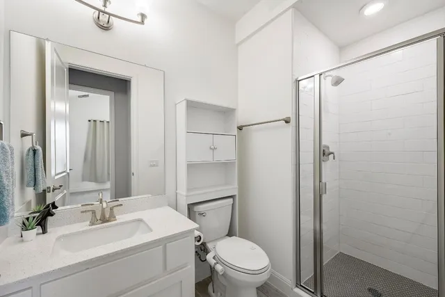 a bathroom with a sink a toilet a mirror and shower