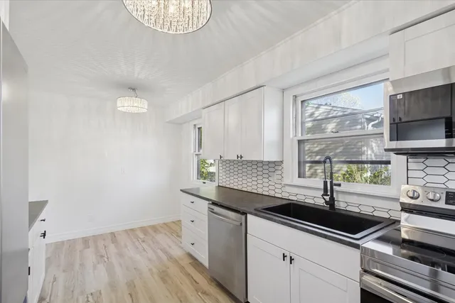 a kitchen with granite countertop a sink a stove and cabinets
