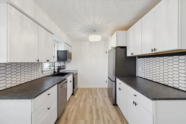 a kitchen with granite countertop white cabinets and stainless steel appliances