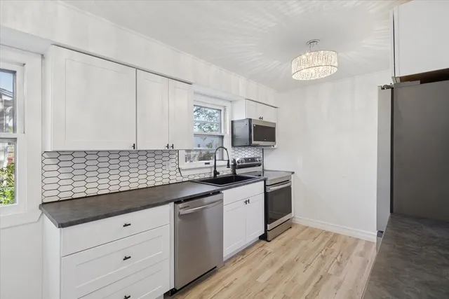 a kitchen with granite countertop stainless steel appliances a sink cabinets and wooden floor