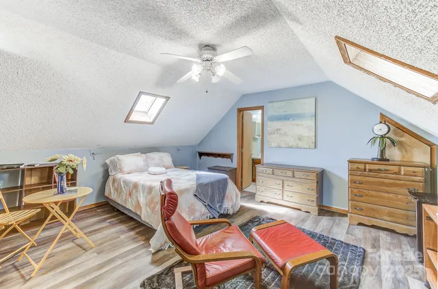 a bedroom with a bed next to a window with workspace