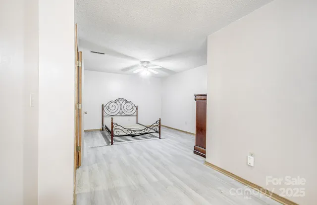 a view of a hallway with wooden floor and a bathroom