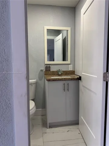 a bathroom with a granite countertop sink and a toilet